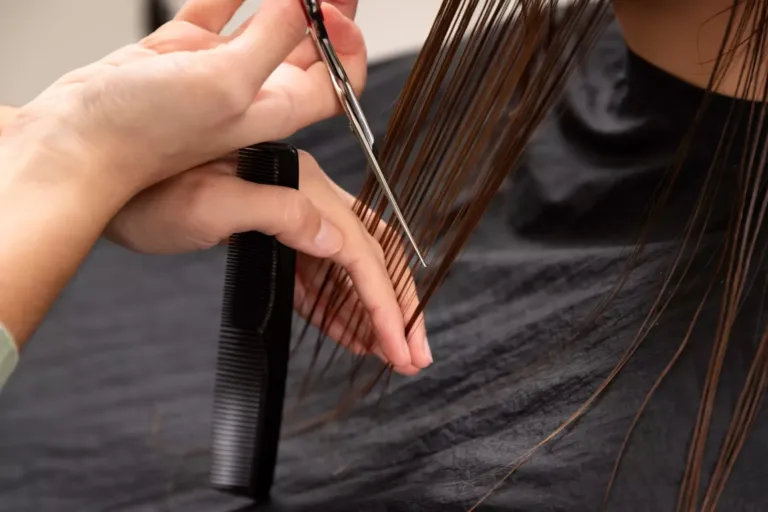 Detalle de unas manos que sujetan cabello mientras lo corta con unas tijeras